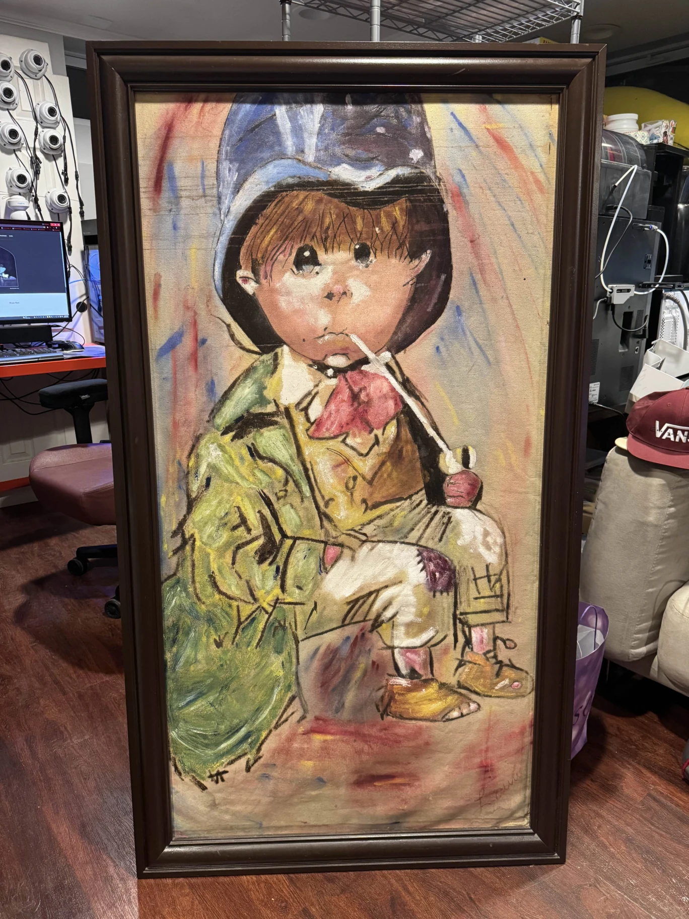A painting of a seated child in a dark cap, green coat, red scarf, and patched trousers, holding a long pipe.